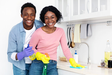 Positive black couple cleaning kitchen furniture together, copy space. Happy african american young...