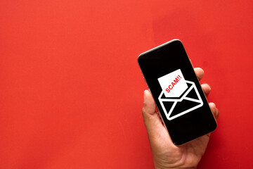 Mobile phone scam and phishing alert. A hand holding a smartphone receives a suspicious email, a...