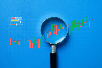 Financial investment research and data analysis concept. A magnifying glass examining a stock...