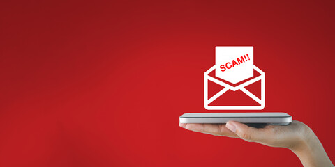 A hand holding a smartphone receives a suspicious email or scam email on red background concept for cybersecurity threat of viruses or data theft,mobile security and protection,phishing alert.