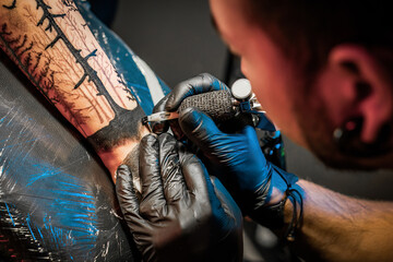 Tattooist doing tattoo for client with machine close-up.Getting tattoo in parlor