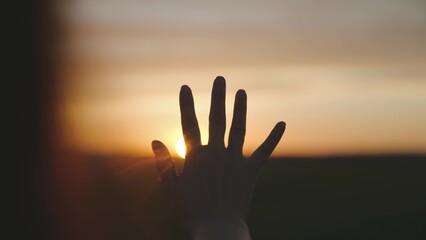Reaching out to the sun, happy girl at sunset, sunlight shining on her hand, solar system star,...
