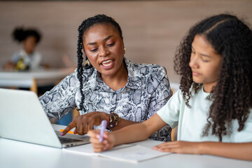 African school teacher is teaching and guiding young student in the class using information from experience and internet for academic literacy study and education