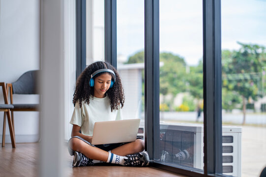 Young African teenager is studying to the audio book class or online course using laptop for remote educational class and knowledge