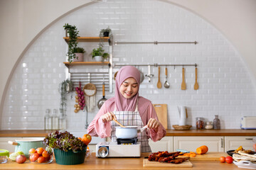 Happy Arab muslim housewife is preparing and cooking food in the kitchen for tasty halal meal at home in Middle east and Persian cuisine culture for Eid Mubarak feast after Ramadan