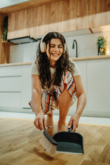 Young caucasian woman cleaning the house while listening to music	