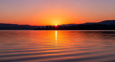 Obraz premium A vibrant sunset reflects on the calm surface of a serene lake