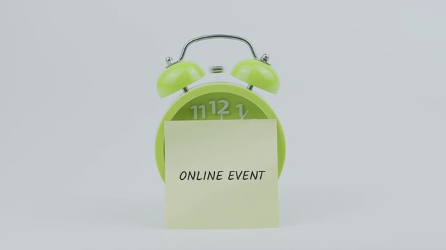 Online Event word written on a sticky note placed in front of a green ringing clock on white background, symbolizing virtual meetings, digital gatherings, and scheduled activities concept illustration