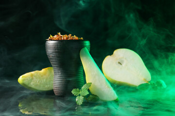 Hookah bowl with pear pieces, mint and smoke on black table, closeup