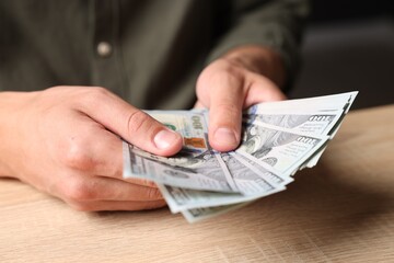 Man counting money at wooden table, closeup