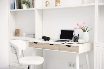 Desk with modern laptop, coffee and stationery in home office