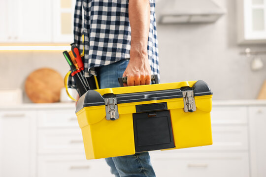 Professional repairman with tool box indoors, closeup