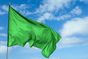 Green flag waving against blue sky outdoors