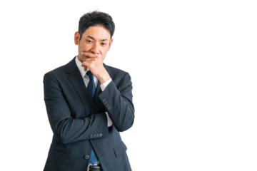 腕組みして考えるスーツ姿のアジア人中年ビジネスマン（悩む・困る・悩み・策士・戦略・作戦・検討）
