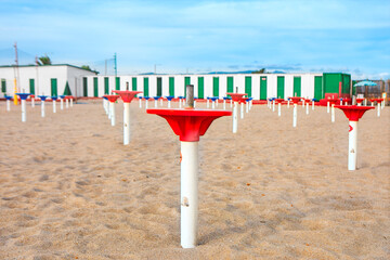 Beachside with numerous umbrella holders mark the sandy area. Beach area marked with umbrella bases