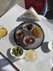 Luxury outdoor dining setup in Italy with wine, Aperol Spritz, olives, and snacks under elegant cover. Chic summer vibes and Mediterranean flavors.