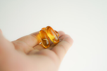 Male hand holding Fish oil capsules with omega 3, omega 9, vitamin D, vitamin E, Cod liver oil