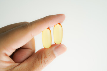 Male hand holding Oil filled capsules, softgel of food supplements, fish oil, omega 3, vitamin E