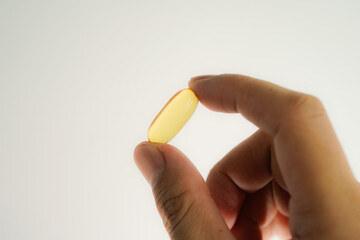 Male hand holding Fish oil capsules with omega 3, omega 9, vitamin D, vitamin E, Cod liver oil