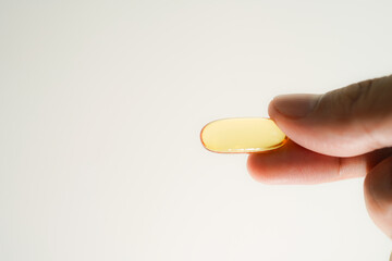 Male hand holding Fish oil capsules with omega 3, omega 9, vitamin D, vitamin E, Cod liver oil