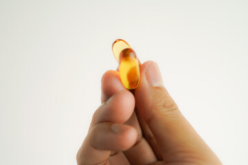 Male hand holding Fish oil capsules with omega 3, omega 9, vitamin D, vitamin E, Cod liver oil