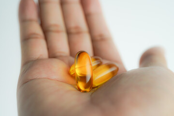 Male hand holding Fish oil capsules with omega 3, omega 9, vitamin D, vitamin E, Cod liver oil