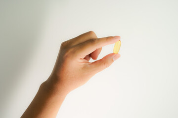 Male hand holding Fish oil capsules with omega 3, omega 9, vitamin D, vitamin E, Cod liver oil