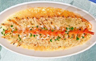 A visually striking dish of steamed prawns, arranged in two rows, topped with copious minced garlic...