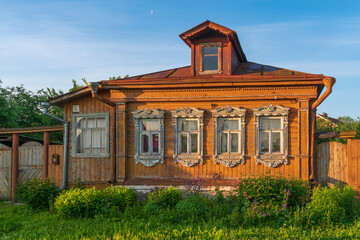 Russian traditional wooden house decorated with house carvings and a front garden on a sunny summer day, Suzdal, Vladimir region, Russia