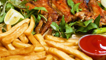 French fries, crispy roasted chicken wings, vibrant lime slices, and fresh herbs creating a mouthwatering meal displayed on a rustic wooden board, perfect for any occasion