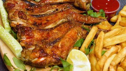 Juicy roasted chicken wings are garnished with fresh herbs and served alongside crispy golden french fries, cucumber slices, and a lemon wedge, creating a mouthwatering and satisfying meal