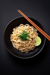 Authentic Thai Cuisine, A fresh serving of Pad Thai noodles with lime and chives in a minimalist black bowl.