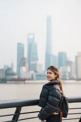 Fototapeta premium woman traveler visiting in Shanghai, China. Happy Female Tourist sightseeing Shanghai view of Lujiazui in The Bund of Shanghai. landmark and popular for tourism attractions. Vacation concept