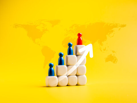 Global population growth concept. Arrow rising up, red and blue wooden figures standing on growth graph steps arranged by white cube blocks, as increase people, isolated on yellow background.
