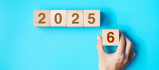 hand holding wooden cube block with 2026 text on blue background. Resolution, plan, review, goal, start and New Year holiday concepts