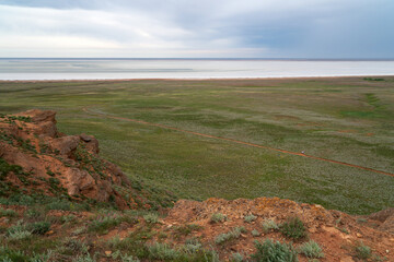 Fancy stones on the slopes of Bolshoe Bogdo Mountain and the salt lake Baskunchak in the distance on a summer day, Bogdinsko-Baskunchak Nature Reserve, Akhtubinsky district, Astrakhan region, Russia