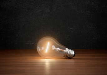 Concept of light bulbs lighting on brown wooden floor in dark color room