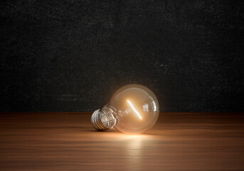 Concept of light bulbs lighting on brown wooden floor in dark color room