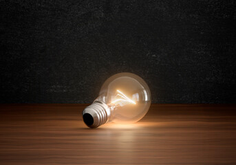 Concept of light bulbs lighting on brown wooden floor in dark color room