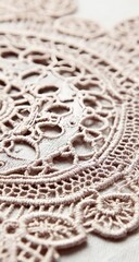 A close-up reveals the intricate details of a delicate beige lace doily. The fine threadwork creates a pattern of floral and geometric shapes on a soft, textured surface