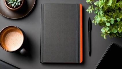 Minimalist workspace coffee, plant, notebook, & tablet on a grey surface, overhead shot. Orange accent on the book adds a pop of color. Black pen included