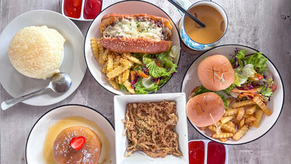 A festive dining table with sandwiches, burgers, pancakes with strawberries, mayonnaise, and salad, fried mushrooms. A cozy dining atmosphere. Friends enjoying dinner.