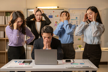 A man is looking at a laptop while three other people look at him