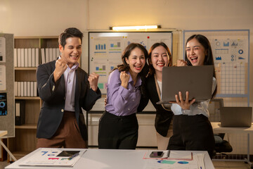 Four women are standing around a table with a laptop