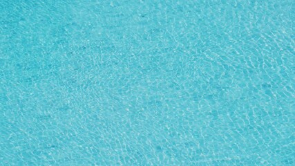 Blue water in the swimming pool with light reflections.,Close-up of clear blue water in a swimming pool with beautiful sunlight reflections and gentle ripples. Relaxing summer background.