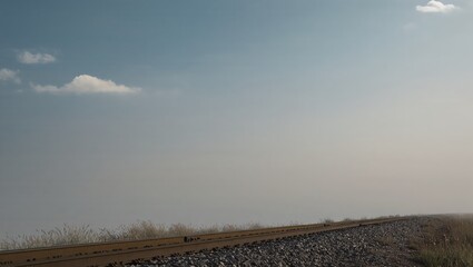 An empty railway track stretches toward the horizon under a hazy sky, evocative of journey, isolation, and solitude.