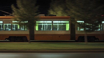 A commuter train glides through the night, windows aglow, highlighting the journey of passengers. Evoking a sense of travel. 