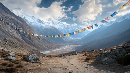 Prayer flags strung across a majestic mountain valley with snow capped peaks and a winding river below