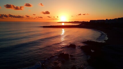 Coastal sunset over calm water.  Silhouetted rocks meet the horizon