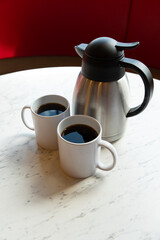 Two Coffee Mugs and Thermos on Marble Table in Café Setting